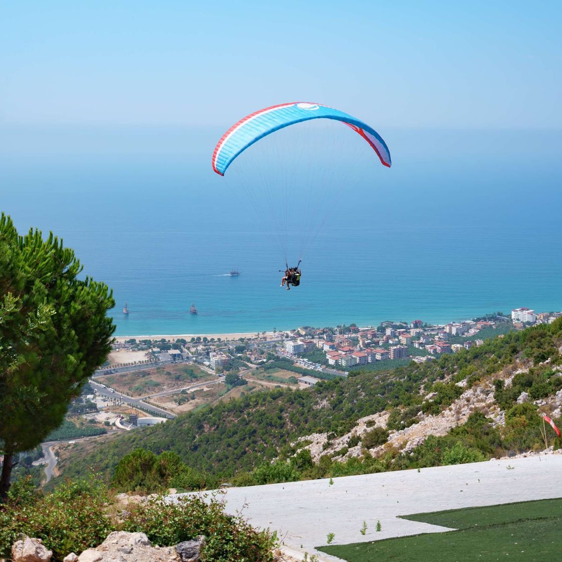 Paraglider flies over a mountain and sea