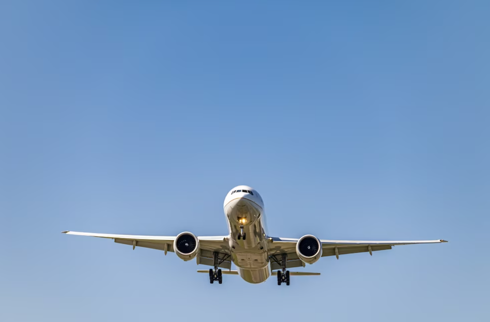 photo from below of a white flying plane in clear blue sky