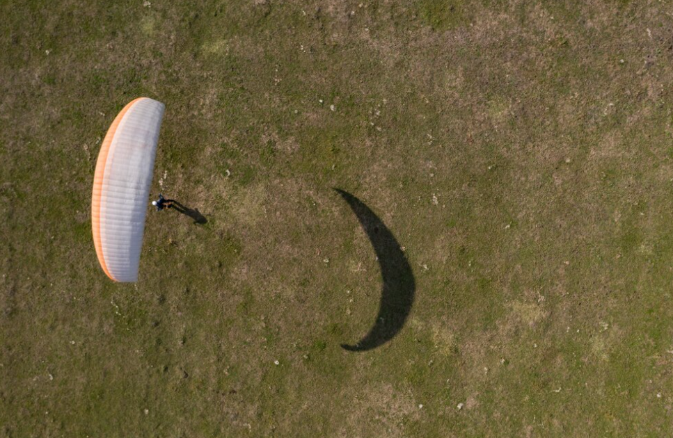 paraglider on green grass and its shadow -  top view